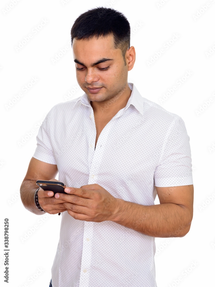 Studio shot of young handsome Indian man using mobile phone isolated against white background Studio shot of young handsome Indian man using mobile phone isolated against white background