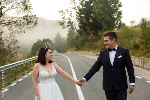 Beautiful wedding couple walking on road near forest © hreniuca