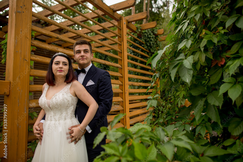 Fototapeta premium Beautiful wedding couple posing in nature at wooden structure