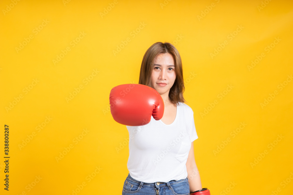Portrait happy young asian woman with boxing glove punching hit or self defend in white t-shirt, Yellow background isolated studio shot and copy space. Portrait happy young asian woman with boxing glove punching hit or self defend in white t-shirt, Yellow background isolated studio shot and copy space.