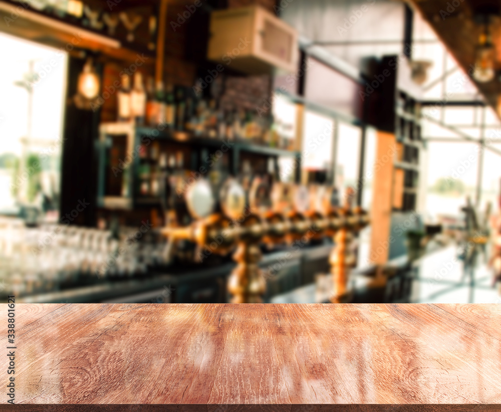 Empty wooden top table in front of abstract blurred beverage bar. Mock up for display of product