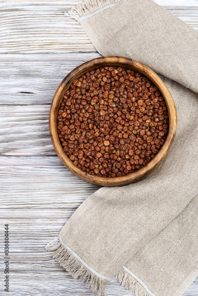 Raw gray peas in round wooden bowl on light wood. Organic healthy diet food. Vertical format image with copy space.