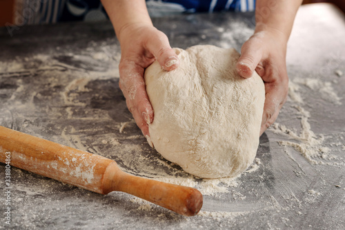 Photography Female hands knead the dough on a table covered in flour.
