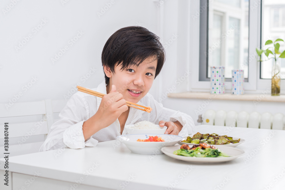 Handsome Asian boy eating with chopsticks