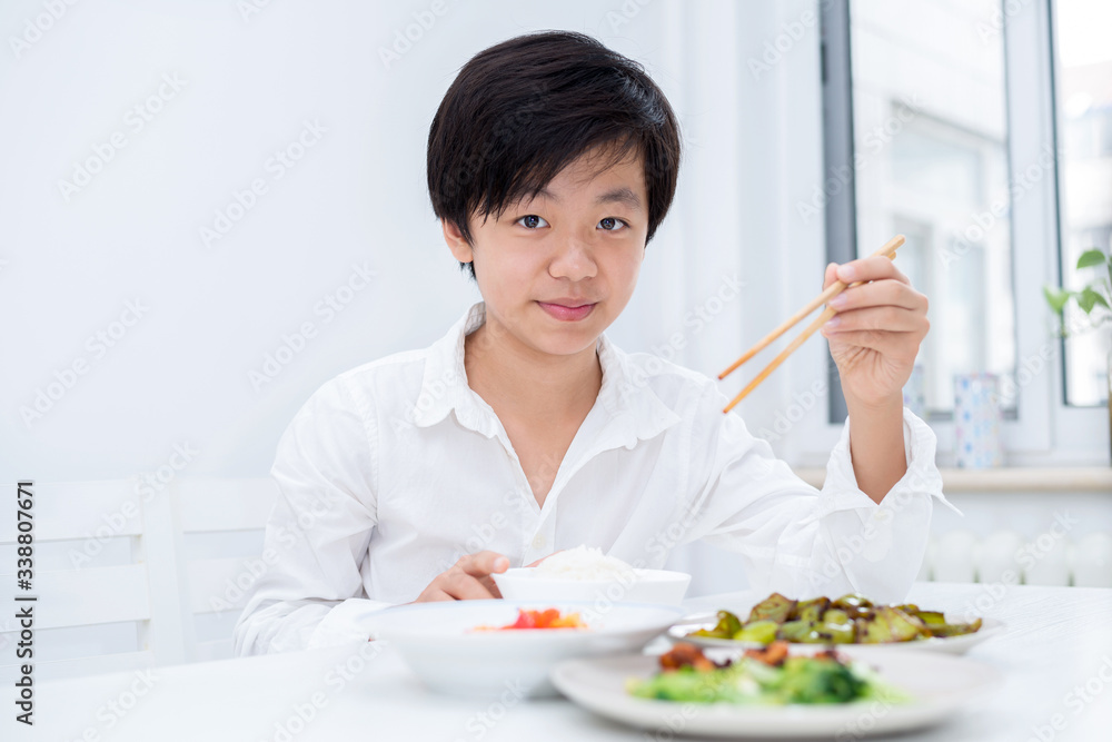 Handsome Asian boy eating with chopsticks Handsome Asian boy eating with chopsticks