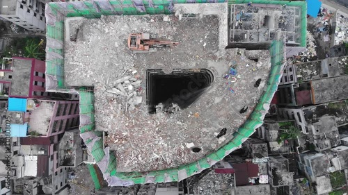 Top floors of building demolished, top-down aerial shot, clearance of old quarter for new development. Small abandoned slum housing units seen around. Camera move up, showing wider view of area photo