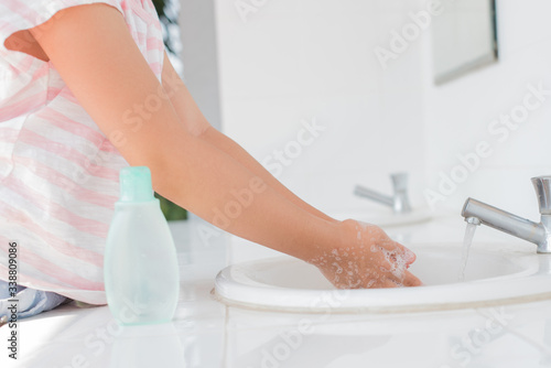 Fototapeta Naklejka Na Ścianę i Meble -  coronavirus pandemic prevention little asian girl is wash hands with soap warm water and rubbing nails and fingers washing frequently or using hand sanitizer gel. hygiene concept hand detail..