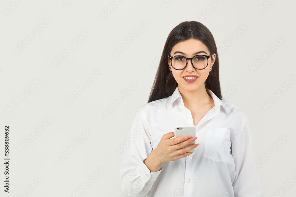 beautiful young woman in glasses on a white background with a phone beautiful young woman in glasses on a white background with a phone