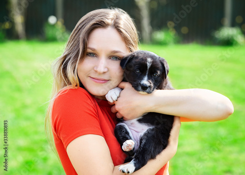 Female model blonde with blue eyes holding up adorable border collie puppy up to cheek