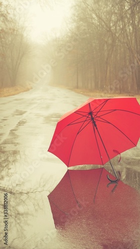 Fototapeta Naklejka Na Ścianę i Meble -  Red umbrella on the rainy ground. During the coronavirus pandemic, no people, no cars, an atmosphere of gray death.