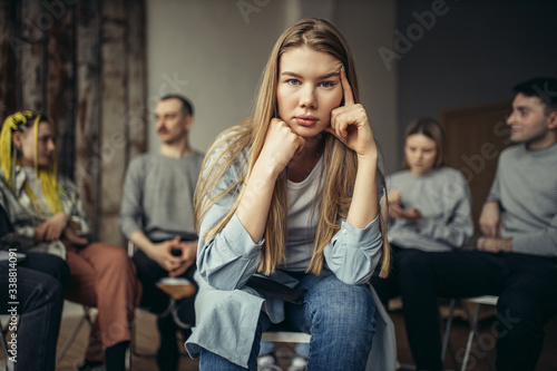 desperate young caucasian woman at a meeting, she sit in the center of isolated room. woman in despair. she needs support and help