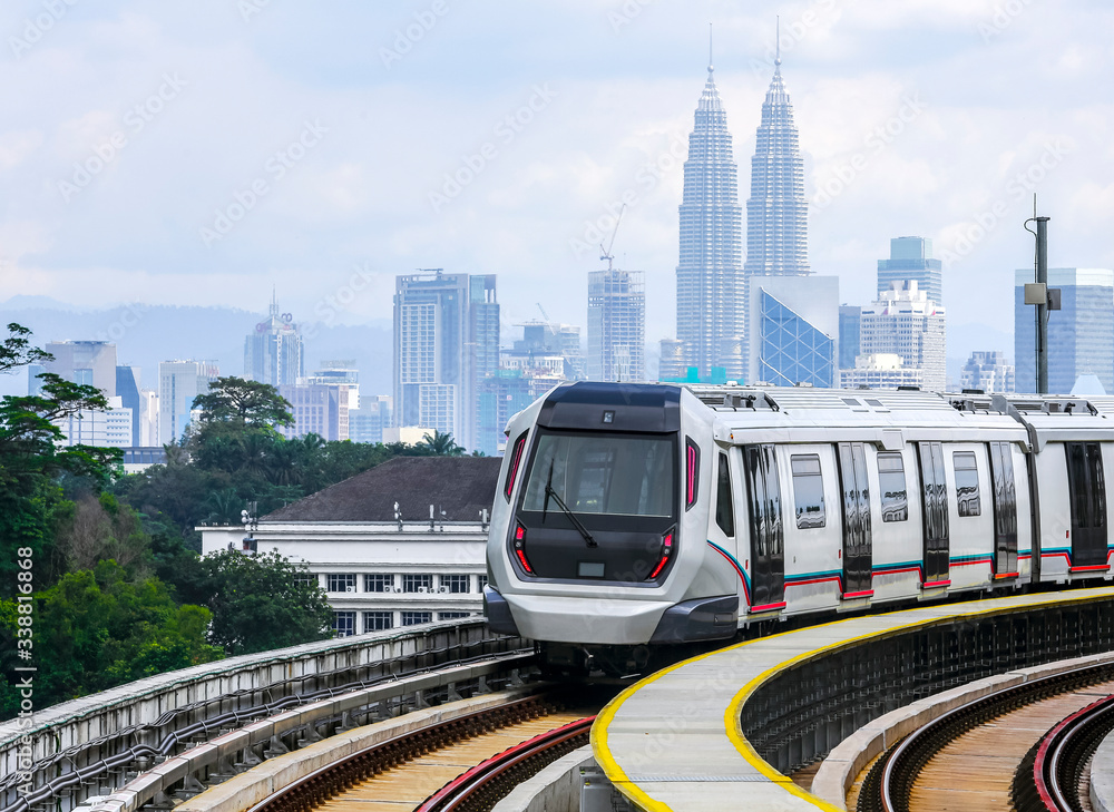 Fototapeta premium Malaysia Mass Rapid Transit (MRT) train with a background of Kuala Lumpur cityscape. People commute with MRT as transportation to work, school, travel, and shopping.