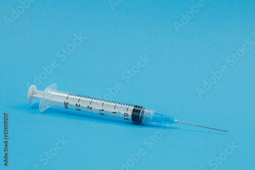 Syringe with needle on a blue background. Selective focus