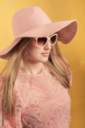 Retro 1960s summerly fashion woman in pink sweater, hat and sunglasses.