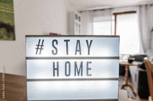 Fototapeta Naklejka Na Ścianę i Meble -  Lightbox sign with hashtag; Stay Home against the background of the interior of the apartment.