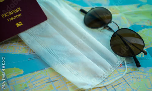 Passport, surgical mask and sunglasses on a city map, showing travel trends during corona virus pandemic era photo