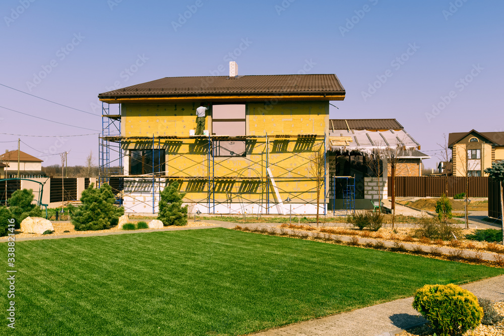 Modern conifer tree garden design and green lawn. House under construction. Pavement path of the garden