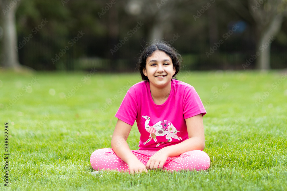 Outdoor Portrait of a Smiling Young Girl Sitting on Grass Outdoor Portrait of a Smiling Young Girl Sitting on Grass