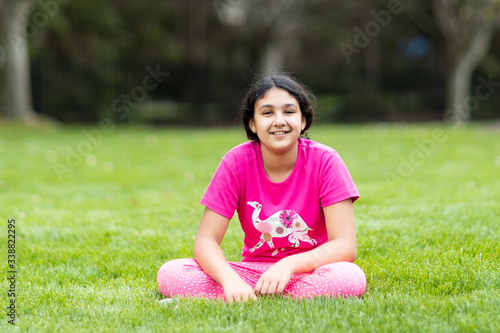 Outdoor Portrait of a Smiling Young Girl Sitting on Grass