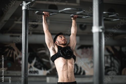 Man during workout in the gym Concept: power, strength, healthy lifestyle, sport. Powerful attractive muscular Man CrossFit trainer do battle workout with ropes at the gym. Young man exercising using