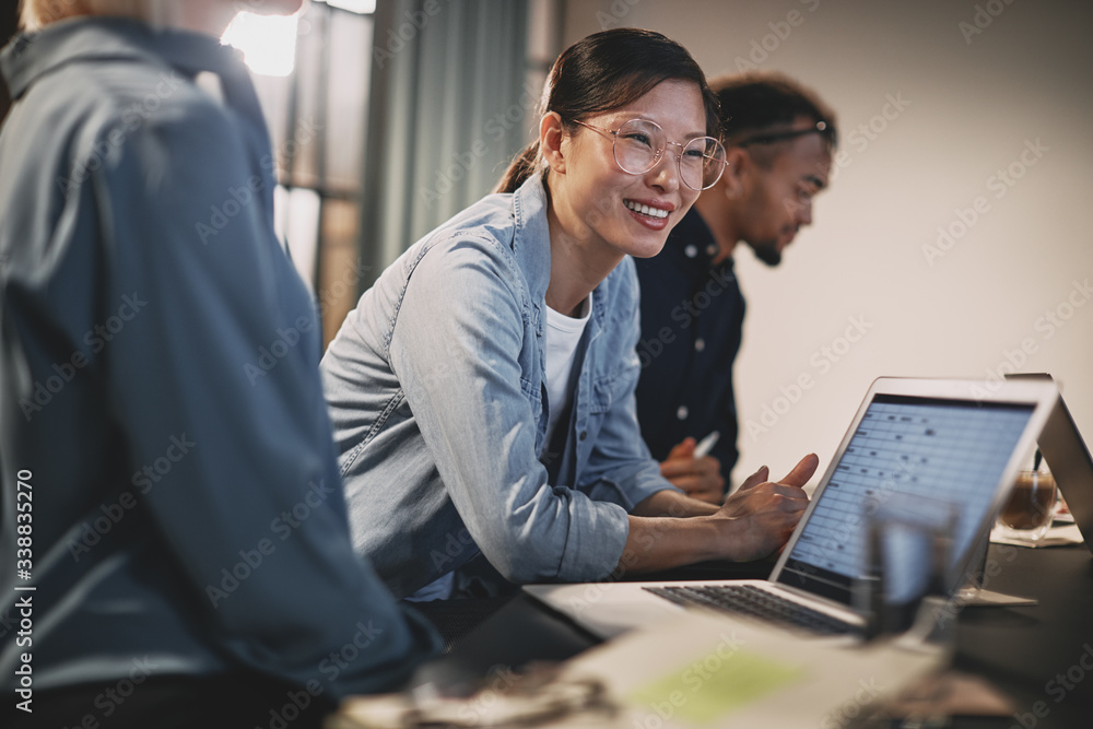 © Flamingo Images - Smiling Asian businesswoman meeting with coworkers in an office © Flamingo Images - Smiling Asian businesswoman meeting with coworkers in an office