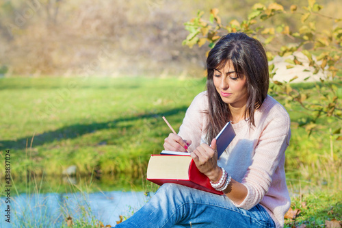 Beautiful Woman Studying Outdoor on a Lake Background 