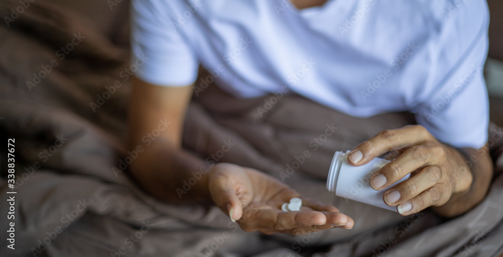Patient hand pours white round medical pills out of  bottle