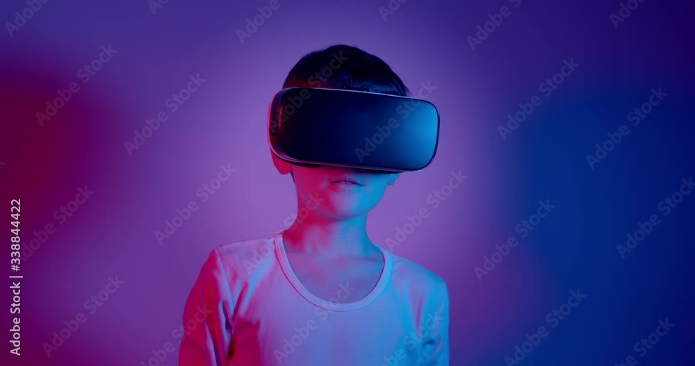 Video Stock Boy wearing VR glasses against blue and purple background. Portrait of 10 year old