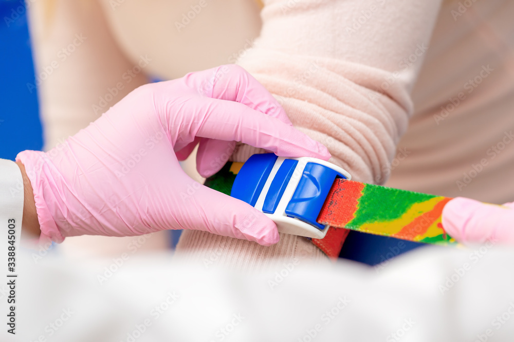 Nurse hand is tightening the harness on the arm to take blood from a vein, close up. Nurse hand is tightening the harness on the arm to take blood from a vein, close up.