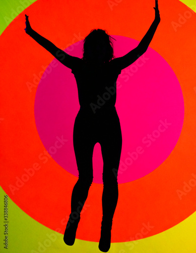 Young, attractive fit woman, jumping up, showing her positive attitude and joy. oval and colorful texture in background 