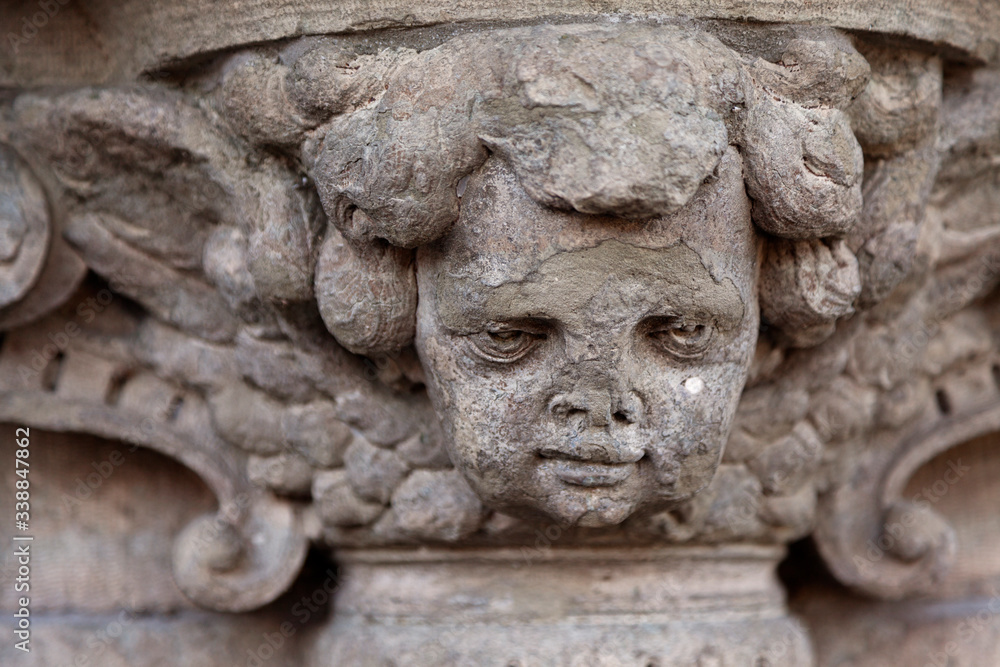 detail of old stone statue placed at door, almost looks like a cherub