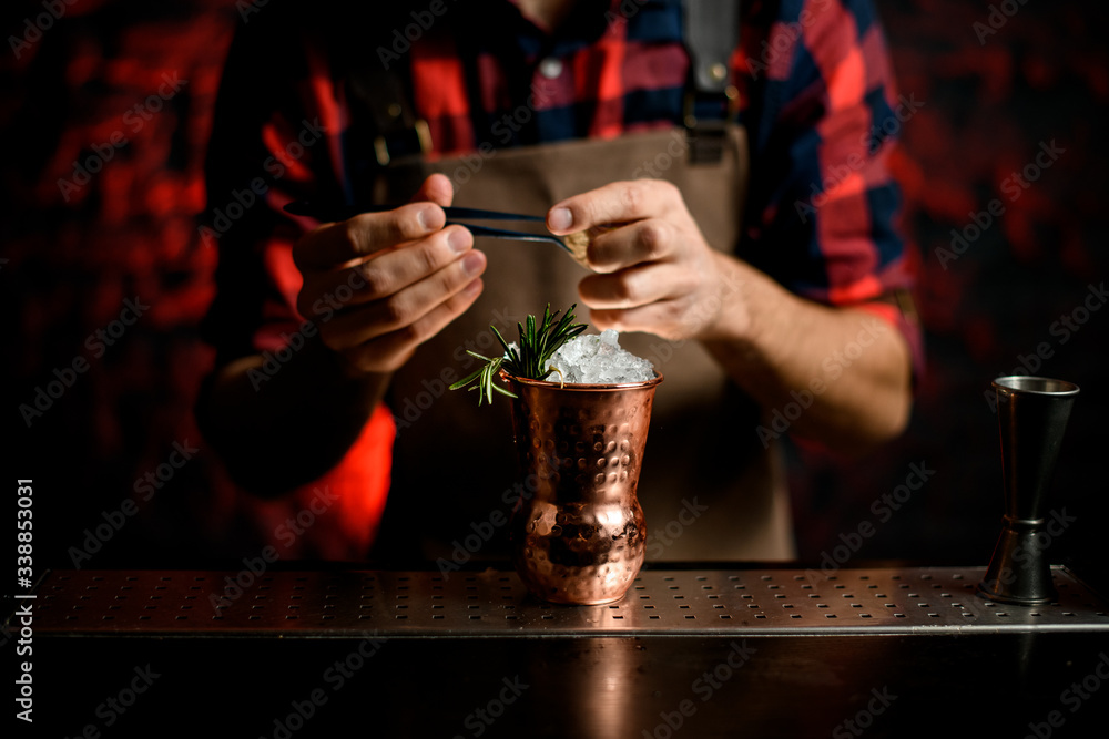 Close-up Barman's hand decorates with spikelet metal glass using tweezers