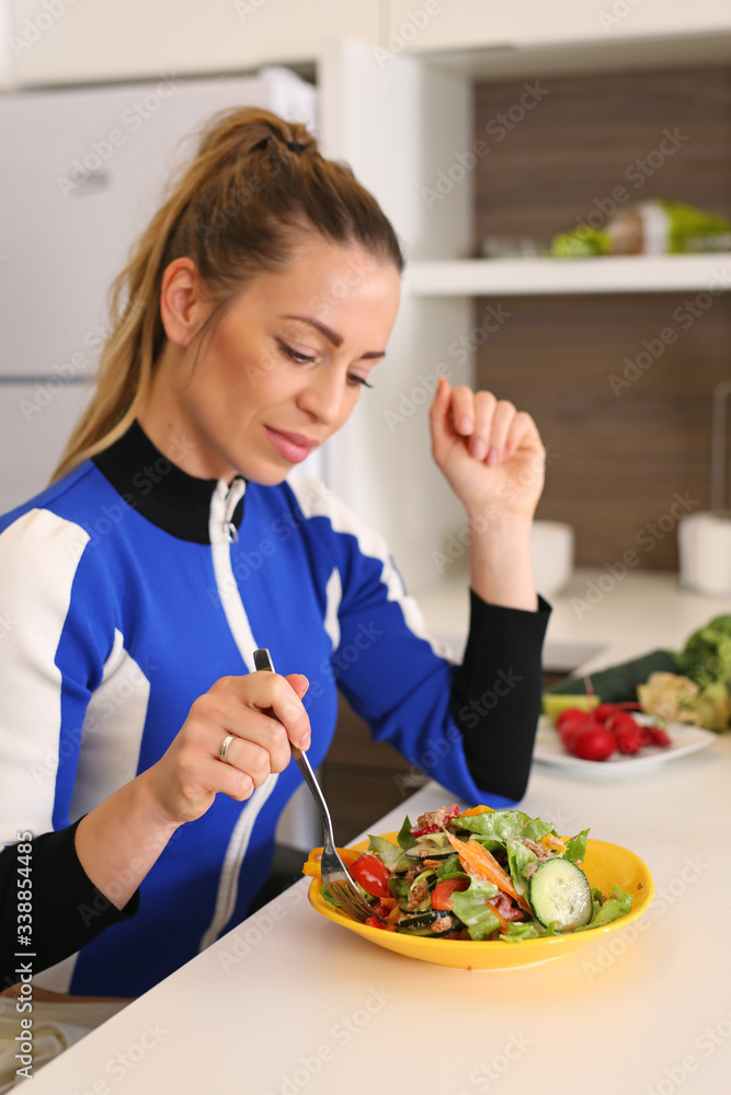 Young woman eating fresh mixed salad in the kitchen Young woman eating fresh mixed salad in the kitchen