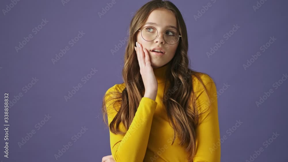 A nice girl is dreaming about something isolated over a purple background in studio A nice girl is dreaming about something isolated over a purple background in studio