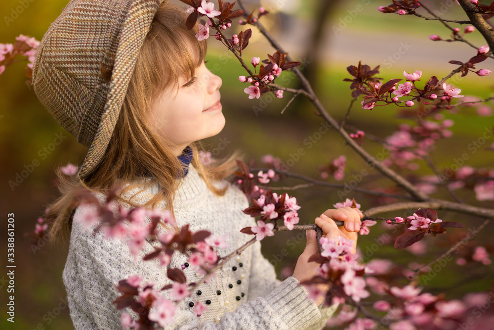 Spring portrait, adorable little girl in hat walk in blossom tree garden Spring portrait, adorable little girl in hat walk in blossom tree garden