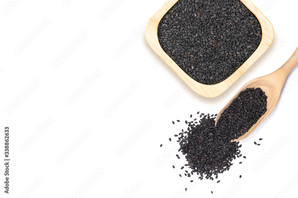 Closeup black sesame seeds in wooden bowl and spoon isolated on white background. Healthy eating concept. Top view. Flat lay. Closeup black sesame seeds in wooden bowl and spoon isolated on white background. Healthy eating concept. Top view. Flat lay.