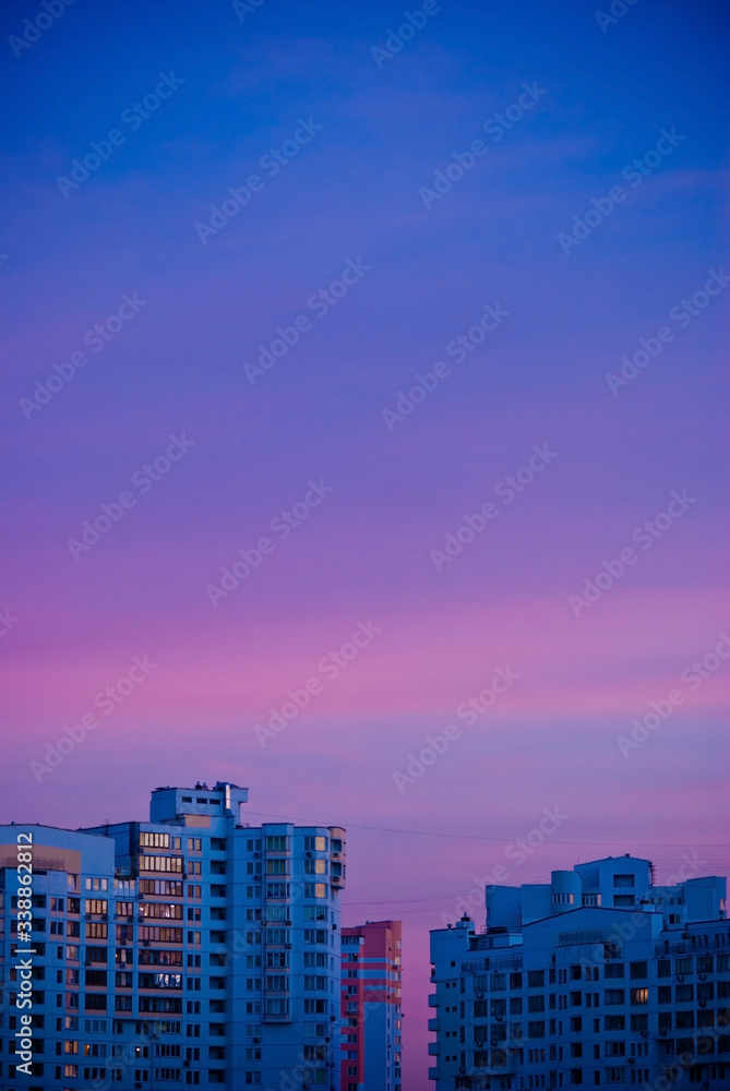 Buildings in city at sunset. City illuminated by the last rays of the setting sun. Magical purple sunset. Minimalism. Place for your text Buildings in city at sunset. City illuminated by the last rays of the setting sun. Magical purple sunset. Minimalism. Place for your text