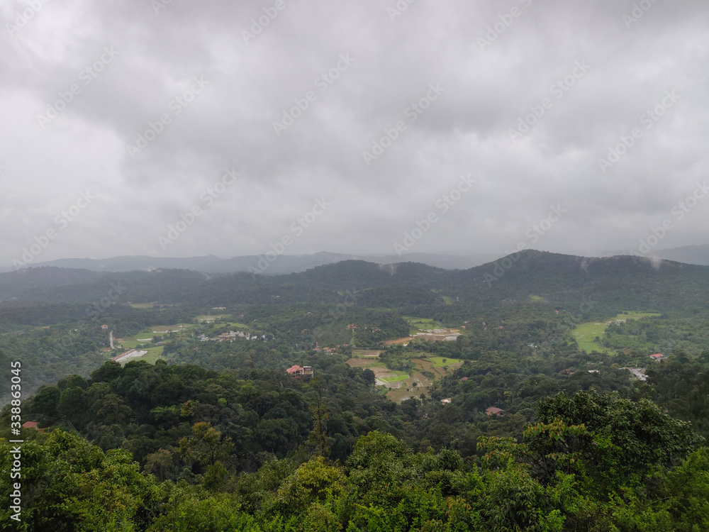 A landscape view of green hills with cloudy sky on the background in Coorg, India.