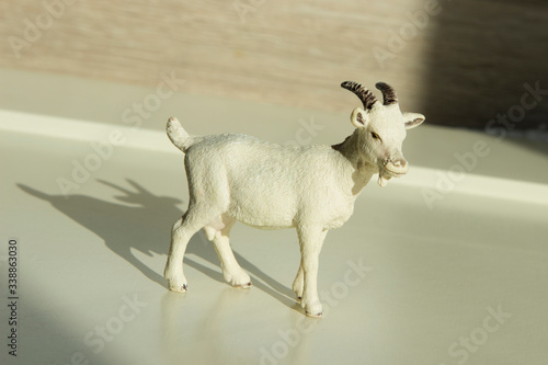 very small toy plastic kid, goatling with shadow on a wooden table photo