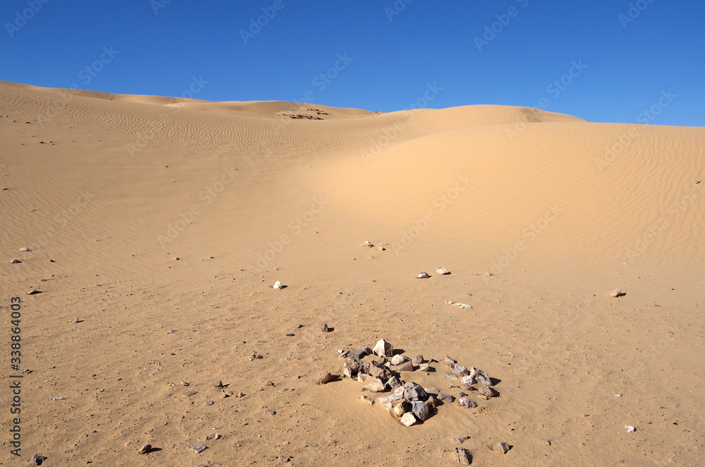 The orange sandy dunes, the dark small stones, the blue sky The orange sandy dunes, the dark small stones, the blue sky