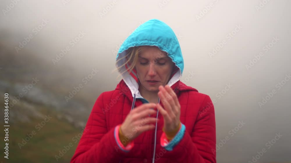 Girl hiker video portrait in the mountains, putting on hood. Cold weather with fog and strong wind in autumn.
Girl hiker video portrait in the mountains, putting on hood. Cold weather with fog and strong wind in autumn.