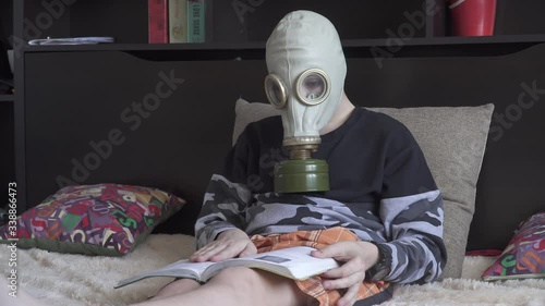 A boy in a gas mask from viruses reads a book