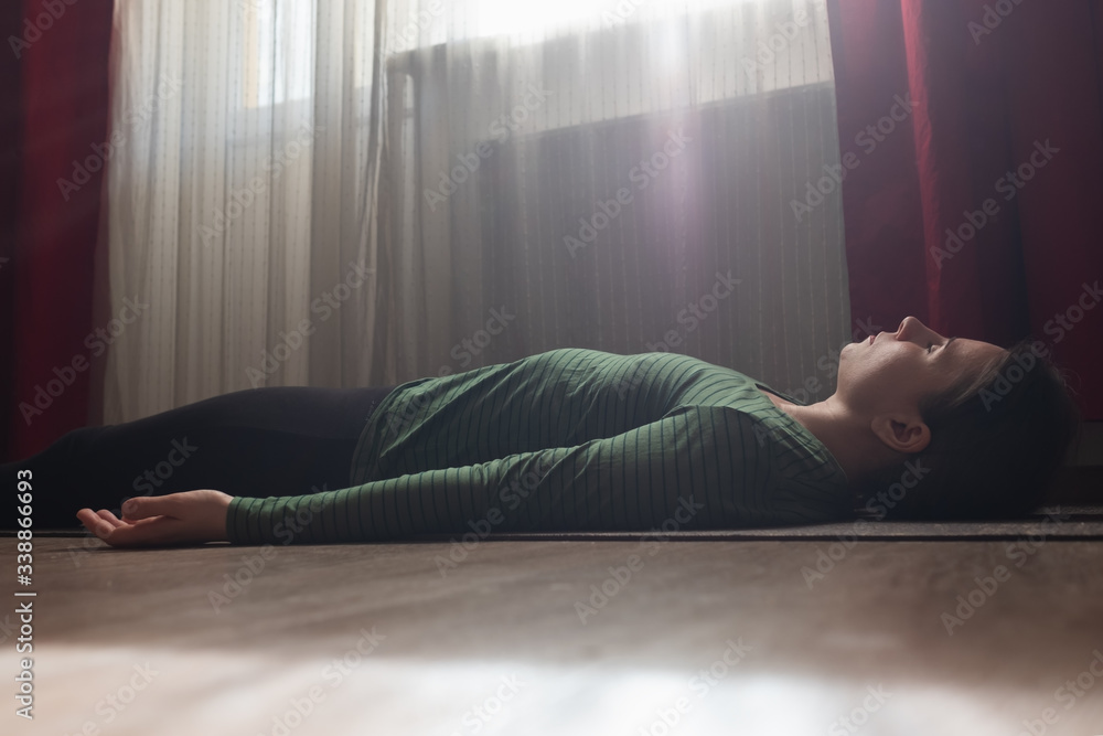 Older woman rests on the floor of the living room in savasana or corpse pose after yoga class Older woman rests on the floor of the living room in savasana or corpse pose after yoga class