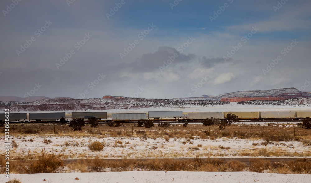 Moving long freight container train along the railroad tracks, transporting and delivering goods across the desert in Arizona.