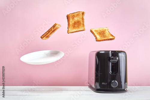 Toasts flew out of modern toaster. Near glass of milk. Levitation food and dish. Delicious morning breakfast