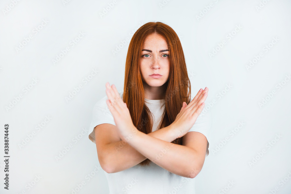 portrait of redheaded young woman looking serious standing on isolated white backgroung holding her arms crossed , body language concept portrait of redheaded young woman looking serious standing on isolated white backgroung holding her arms crossed , body language concept