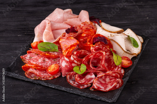 Meat plate with pieces from different varieties of meat, served with greens and cherry tomatoes