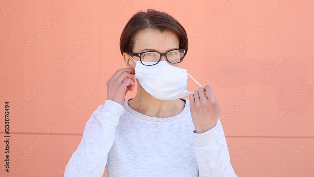 A woman takes off a medical mask and smiles. Girl joyfully removes the mask.