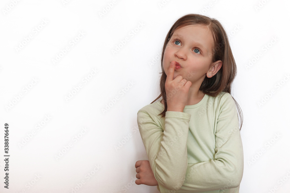 The conceived girl on a white gray background holds the index finger near the mouth The conceived girl on a white gray background holds the index finger near the mouth