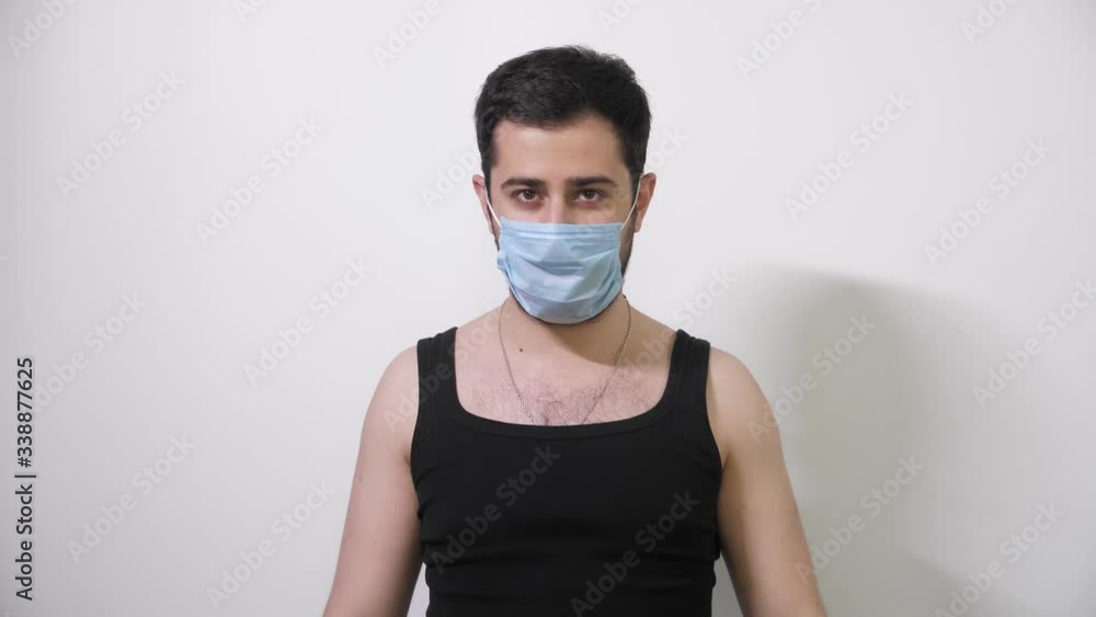 Caucasian man puts on his medical mask looks into camera and shows the stop sign Covid19 Coronavirus Caucasian man puts on his medical mask looks into camera and shows the stop sign Covid19 Coronavirus